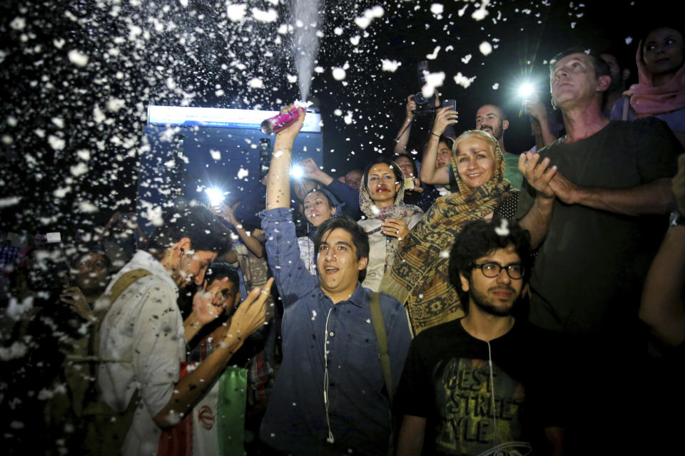 FILE - A group of jubilant Iranians cheer and spray artificial snow during street celebrations following a landmark nuclear deal, in Tehran, Iran, Tuesday, July 14, 2015. While the world’s attention has been focused on Ukraine, the Biden administration also has been racing forward with other global powers toward restoring the 2015 international nuclear deal with Iran. In Feb. 2022, after months of negotiations in Vienna, the various sides have indicated a new deal is close, perhaps in the coming days. (AP Photo/Ebrahim Noroozi, File)