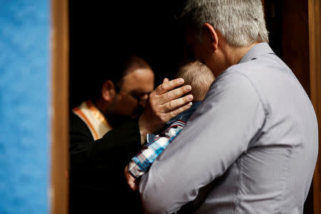 An Orthodox priest touches the head of the first baby born on the islet of Thymaina after six years, with the financial support of the Aegean Team doctors, during the baptism on the islet of Ayios Minas, Greece, May 12, 2017. REUTERS/Alkis Konstantinidis