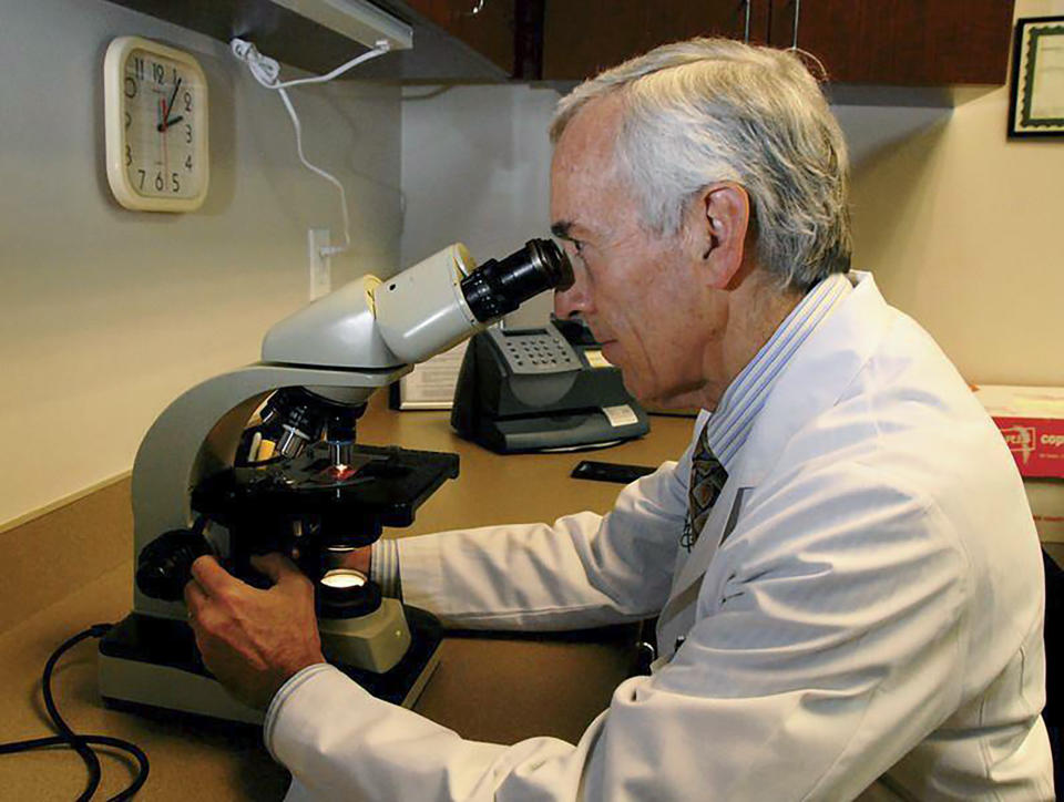 In this undated photo provided by Atlanta Allergy & Asthma, Dr. Stanley Fineman looks through a microscope at Atlanta Allergy & Asthma Center in Atlanta to examine the pollen. When Fineman started 40 years ago as an allergist in Atlanta, he told patients they should start taking their medications and prepare for the onslaught of pollen season around St. Patrick’s Day. Now he tells them to start around St. Valentine’s Day. (Robin B. Panethere /Atlanta Allergy & Asthma via AP)