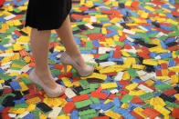 LONDON, ENGLAND - JANUARY 24: A woman stands on a carpet with a Lego brick design at the 2012 London Toy Fair at Olympia Exhibition Centre on January 24, 2012 in London, England. The annual fair which is organised by the British Toy and Hobby Association, brings together toy manufacturers with retailers from around the world. (Photo by Oli Scarff/Getty Images)