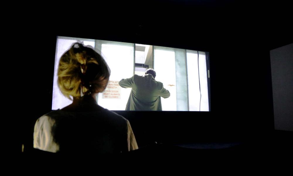 A woman views a video piece by Naeem Mohaiemen at Tate Britain