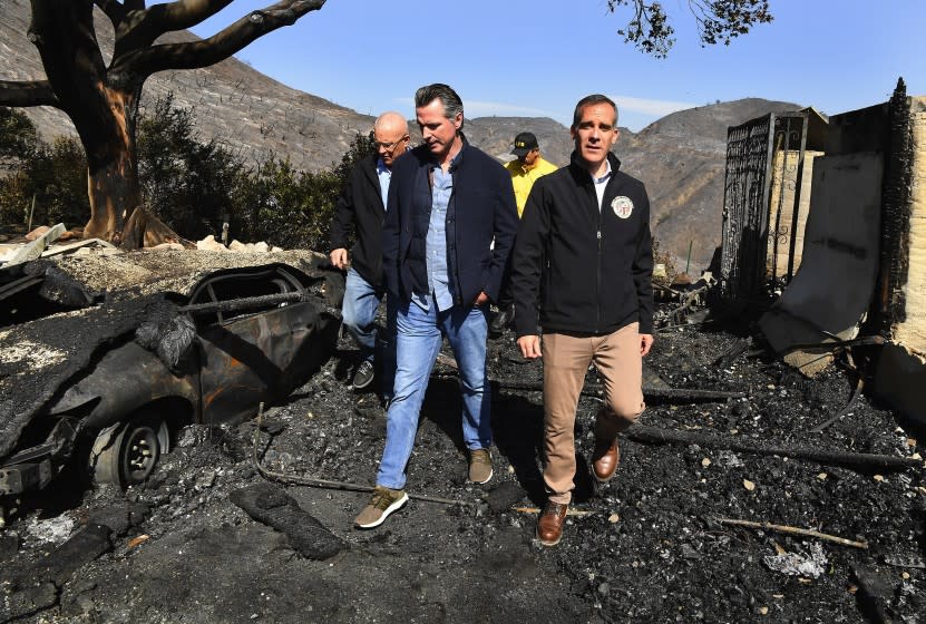 Wally Skalij  Los Angeles Times GOV. GAVIN NEWSOM, center, looks over the fire devastation in Brentwood with L.A. Mayor Eric Garcetti, right, and Councilman Mike Bonin, left rear. Newsom and the state face dual crises in blackouts and wildfires.