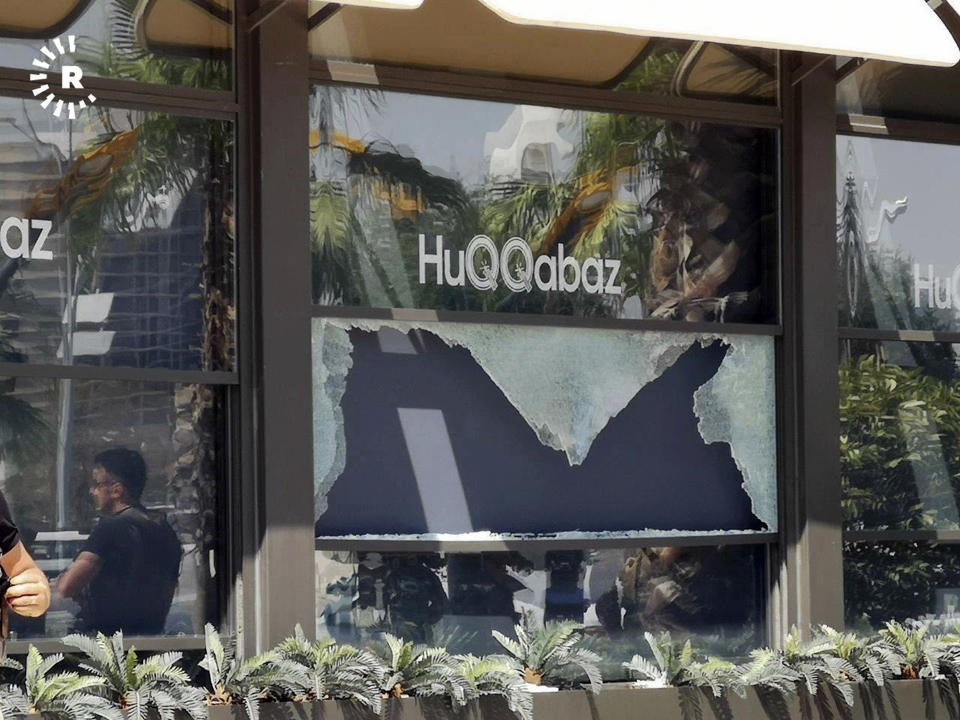 This image posted by RUDAW Facebook TV, an Irbil-based Kurdish broadcaster, shows broken glass shows in the window of a restaurant that was the scene of a shooting, in Irbil, Iraq, Wednesday, July 17, 2019. Turkey's state-run news agency says a Turkish diplomat working at Ankara's consulate in the northern Iraqi city of Irbil was killed during a shooting attack inside the restaurant there. (RUDAW Facebook TV via AP)