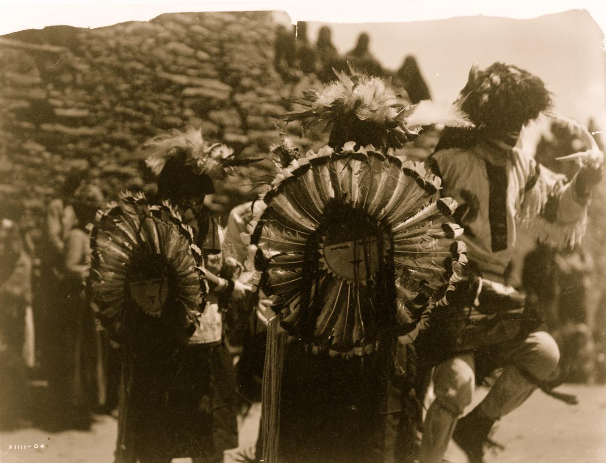 Costumed dancers wearing dance bustles of Tewa sun god made of turkey feathers
