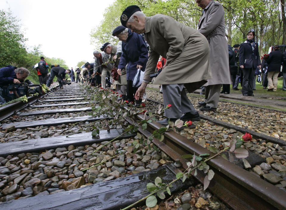 In this Monday May 9, 2015, file photo, Canadian World War II veterans put roses on the railroad tracks at former concentration camp Westerbork, the Netherlands, remembering more than a hundred thousand Jews who were transported from Westerbork to Nazi death camps. The Dutch national railway company NS says it will set up a commission to investigate how it can pay individual reparations for its role in mass deportations of Jews by Nazi occupiers during World War II. (AP Photo/Peter Dejong)