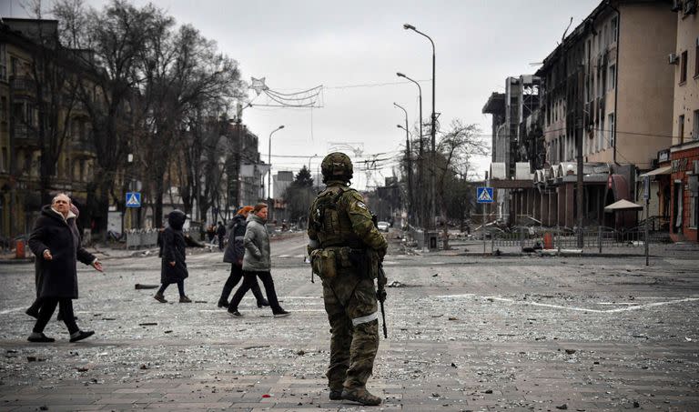 TOPSHOT - Un soldado ruso observa el paso de ciudadanos ucranianos en Mariupol (Photo by Alexander NEMENOV / AFP)