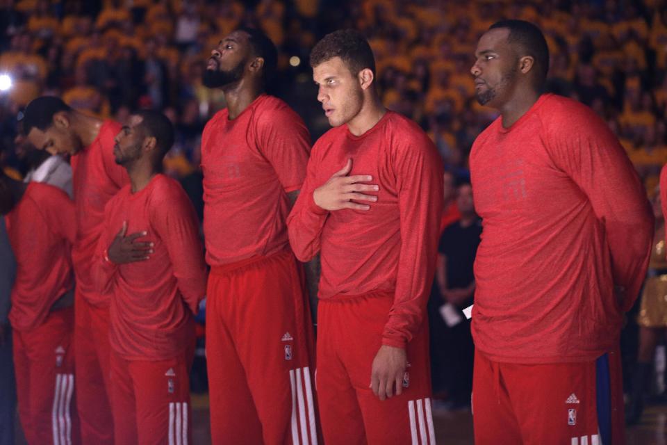 Los jugadores de los Clippers escuchan el himno con sus camisetas al revés en protesta por los comentarios racistas del dueño del equipo, Donald Sterling, el domingo, 27 de abril de 2014, en Oakland, California. El comisionado de la NBA, Adam Silver, suspendió a Sterling de por vida y lo multó 2,5 millones de dólares. (AP Photo/Marcio Jose Sanchez)