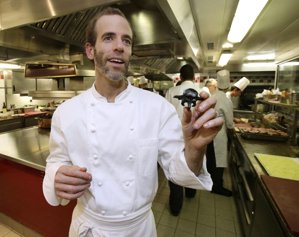 This Oct. 9, 2012 photo shows American Chef Dan Barber holding a pig bone in the kitchen of the Plaza Athenee in Paris. He fires up the succulent pork over gnarled, carbonated pig bones, grows sweet greens in a soil mixed with pumice that's left over by the hazelnut oil industry and he's creating a new kind of wheat, named after himself _ Dan Barber. (AP Photo/Michel Euler)