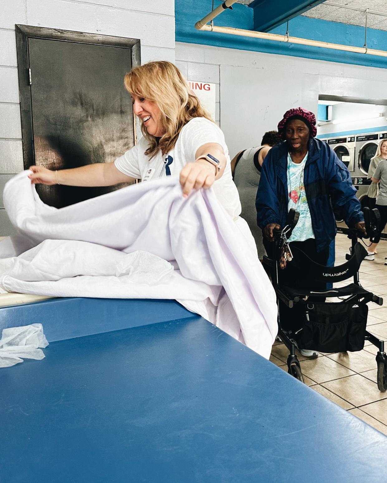 At a Jacksonville laundromat, a volunteer handles laundry for a customer at a recent free laundry session organized by the Laundry Project.