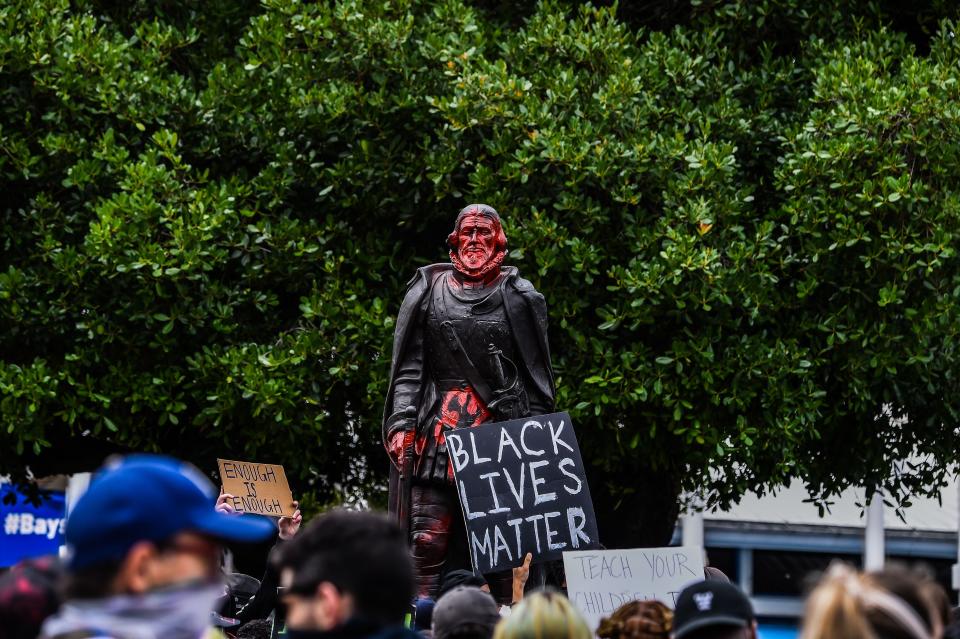 Protestors gather around a vandalised statue of Former Governor of Puerto Rico, Juan Ponce de Leon in Downtown Miami on June 12, 2020 in Miami. (Photo by CHANDAN KHANNA / AFP)