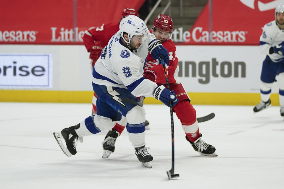 Tampa Bay Lightning center Tyler Johnson (9) shoots as Detroit Red Wings left wing Darren Helm (43) defends in the first period of an NHL hockey game Tuesday, March 9, 2021, in Detroit. (AP Photo/Paul Sancya)