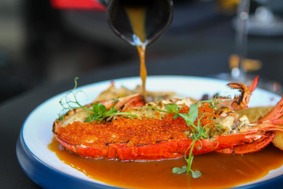 Close up of broth being poured onto lobster dish