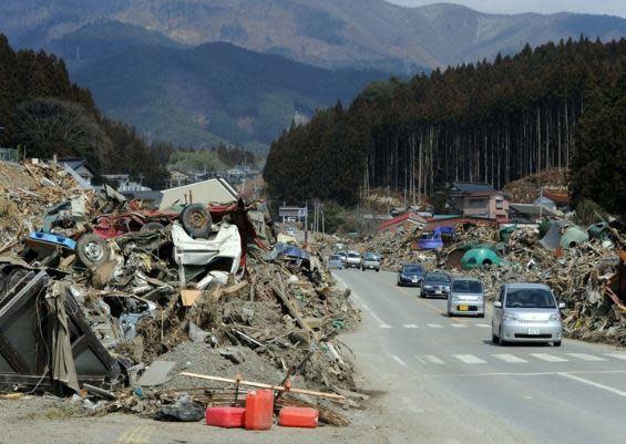 Vehicles drive past debris piled up in Rikuzen-Takata, in Japan's northern Iwate prefecture, March 29, 2011, not long after a massive earthquake and deadly tsunami hit the region. / Credit: TOSHIFUMI KITAMURA,KAZUHIRO NOGI/AFP/Getty