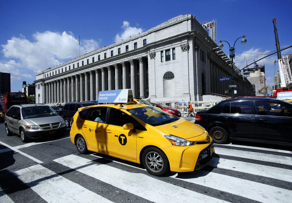 FILE - In this Aug. 15, 2016 file photo, a taxi drives past the James A Farley Post Office Building in New York. The city of New York and the state of California sued the U.S. Postal Service Tuesday, Oct. 22, 2019, to stop tens of thousands of cigarette packages from being mailed from foreign countries to U.S. residents, saying the smugglers are engaging in “cigarette tax evasion” while postal workers look the other way. (AP Photo/Mark Lennihan, File)