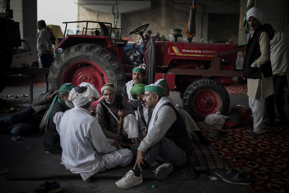 FILE - In this Saturday, Dec. 5, 2020, file photo, farmers huddle together as they share a hookah while blocking a major highway during a protest against new farm laws at the Delhi-Uttar Pradesh state border, India. The protests gained momentum in November when the farmers tried to march into New Delhi but were stopped by police. Since then, they have promised to hunker down at the edge of the city until the laws are repealed. (AP Photo/Altaf Qadri, File)