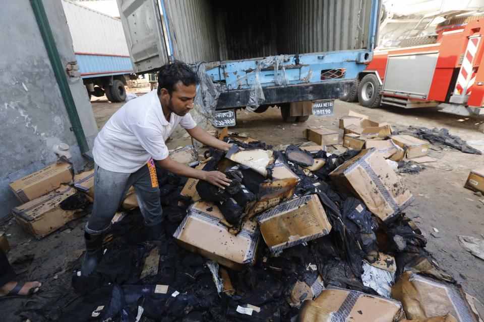 An employee looks at boxes of clothes damaged when a vehicle was set on fire by protesting workers, at a Standard Group garment factory in Gazipur