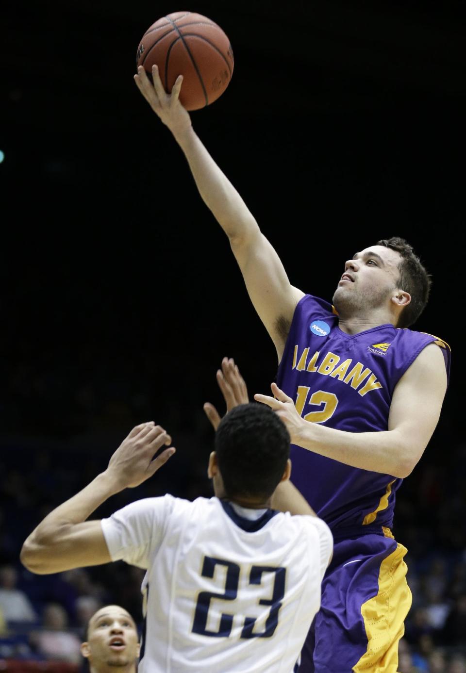 Albany guard Peter Hooley (12) drives against Mount St. Mary's guard Julian Norfleet (23) during the first half of a first-round game of the NCAA college basketball tournament, Tuesday, March 18, 2014, in Dayton, Ohio. (AP Photo/Al Behrman)