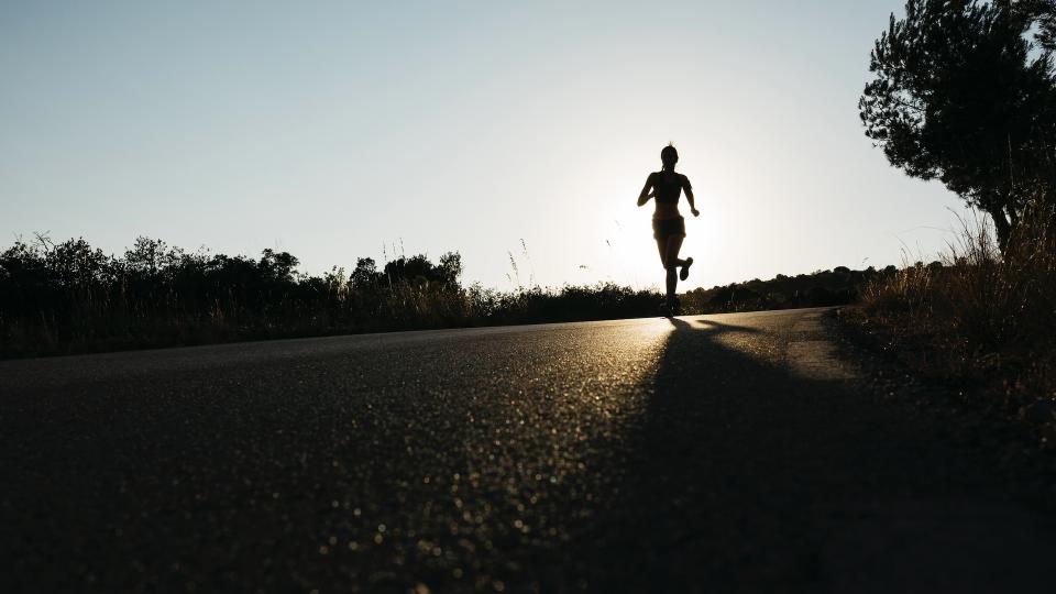 Person running on road at sunset