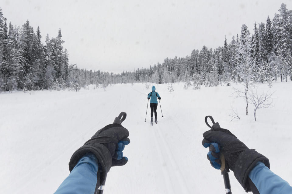 Two people cross country skiing through the Finnish countryside