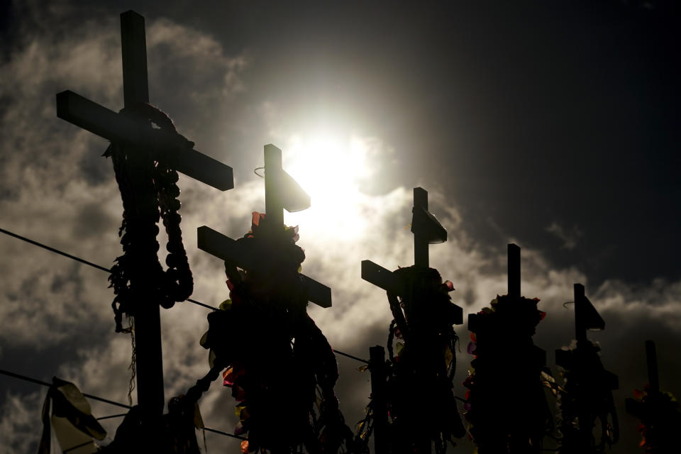 FILE - Leis and flowers adorn crosses at a memorial for victims of the August wildfire above the Lahaina Bypass highway, Wednesday, Dec. 6, 2023, in Lahaina, Hawaii. (AP Photo/Lindsey Wasson, File)