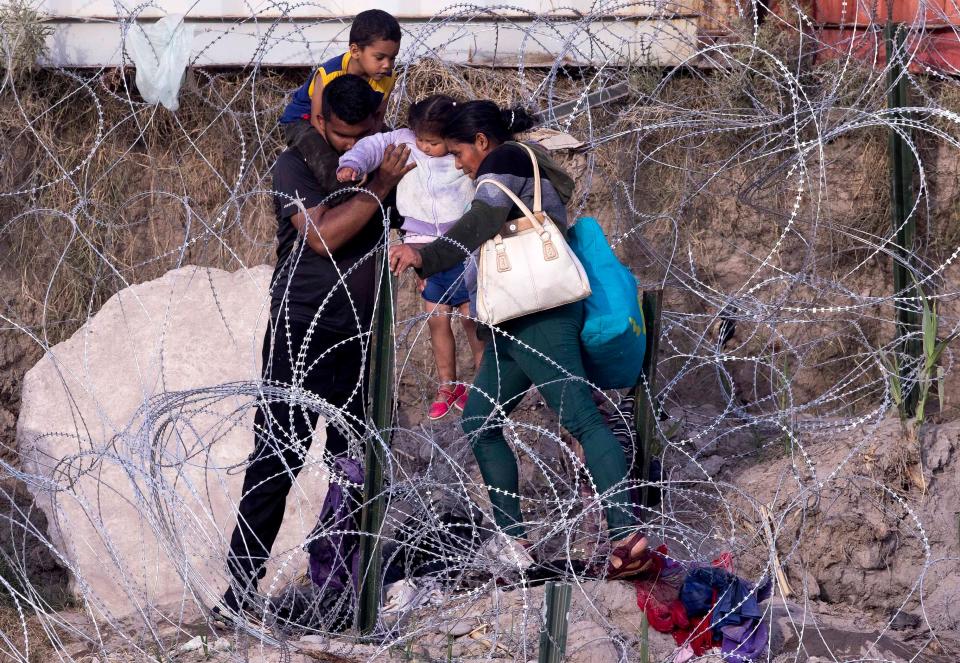 Migrants breach a section of concertina wire after crossing the Rio Grande River on July 20, 2023, from Piedras Negras, Coahuila, Mexico into Eagle Pass, Texas hoping to seek asylum in the U.S.