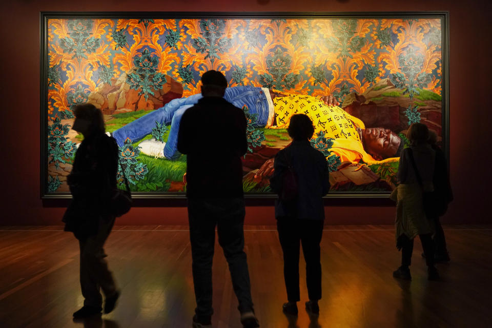 People look at a painting by Kehinde Wiley titled "Femme piquée par un serpent," at the de Young Museum in San Francisco, Friday, March 24, 2023. The painting is part of the "Kehinde Wiley: An Archaeology of Silence," exhibition. (AP Photo/Godofredo A. Vásquez)