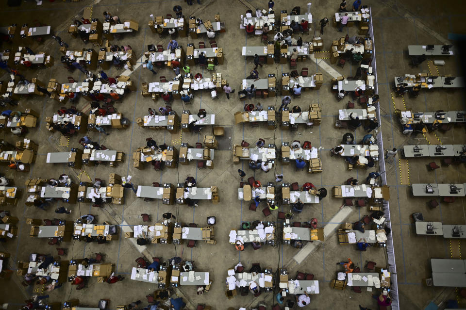 Officials count early votes at the Roberto Clemente Coliseum where social distancing is possible amid the COVID-19 pandemic, during general elections in San Juan, Puerto Rico, Tuesday, Nov. 3, 2020. In addition to electing a governor, Puerto Ricans are voting in a nonbinding referendum on statehood. (AP Photo/Carlos Giusti)