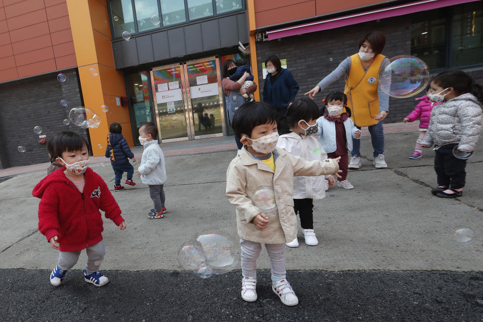 Children wearing face masks to help protect against the spread of the coronavirus watch soap bubbles fly at the Chogyesa temple in South Korea, April 24, 2020. (AP Photo/Ahn Young-joon)