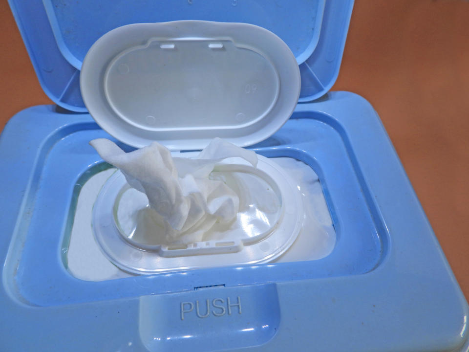 Wet wipe emerging from a plastic dispenser labeled "PUSH," highlighting ease of use and accessibility