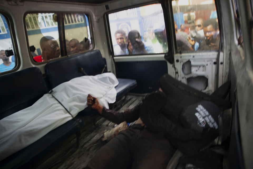 People look into the window of a police car carrying the bodies of two people killed in a shooting with police in Port-au-Prince, Haiti, Thursday, July 8, 2021. According to Police Chief Leon Charles, the two dead are suspects in the assassination of Haitian President Jovenel Moïse. (AP Photo/Joseph Odelyn)