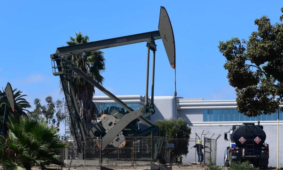 A worker pulls a line from a pumpjack in an oil well in Signal Hill, south of Los Angeles, California.