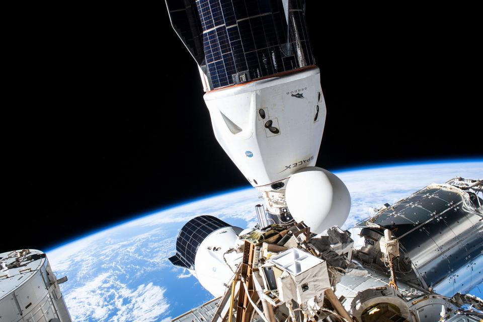 Two U.S spacecraft, the SpaceX Cargo Dragon (foreground) and the SpaceX Crew Dragon (bottom center), are pictured docked to the Harmony module's international docking adapters.