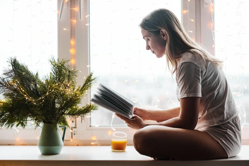 Actual picture of me, sitting on a table with my fairy lights on, reading a book (Getty Images/iStockphoto)