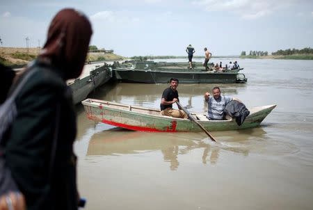 A displaced Iraqi girl looks at her father as he holds the body of his wife, who was killed during the fighting in Mosul, on a boat before crossing the Tigris River after the bridge has been temporarily closed, in western Mosul, Iraq May 6, 2017. REUTERS/Suhaib Salem