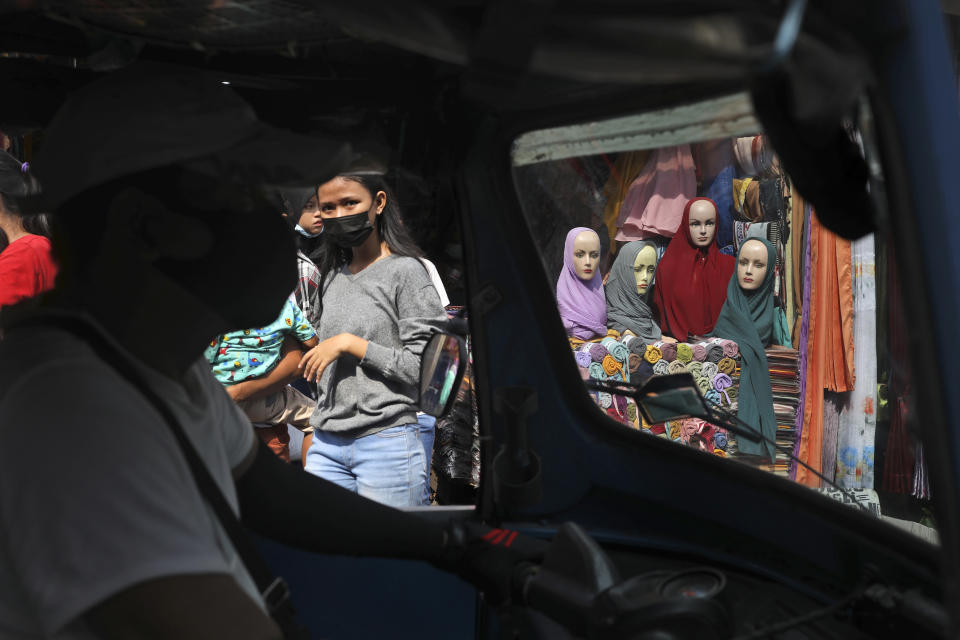 Mannequins and women wearing masks to curb the spread of coronavirus outbreak are seen through the windows of a three-wheeled motorized taxi called "bajaj", during the last week of Ramadan at a market in Jakarta, Indonesia, Tuesday, May 4, 2021. People flock markets and shopping malls in the capital as they shop for food and new clothings in preparation for Eid al Fitr holiday that marks the end of the holiest month in Islamic calendar. (AP Photo/Dita Alangkara)