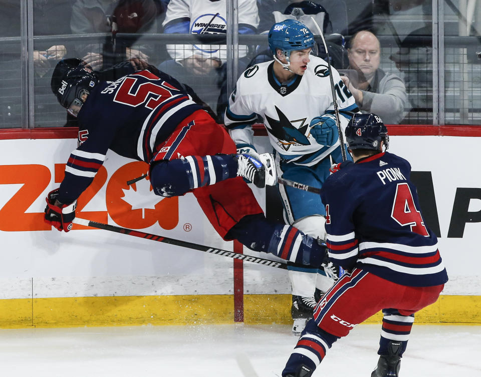 Winnipeg Jets' Mark Scheifele (55) and San Jose Sharks' William Eklund (72) collide as Jets' Neal Pionk (4) defends during the first period of an NHL hockey game Wednesday, Feb. 14, 2024, in Winnipeg, Manitoba. (John Woods/The Canadian Press via AP)