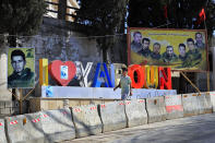 A Lebanese youth walks next to portraits of killed Hezbollah fighters in the Lebanese-Israeli border village of Yaroun, south Lebanon, Saturday, Aug. 13, 2022, where the parents of Hadi Matar emigrated from. On Friday, Matar, 24, born in Fairview, N.J., attacked author Salman Rushdie during a lecture in New York. His birth was a decade after "The Satanic Verses" was first published. (AP Photo/Mohammed Zaatari)