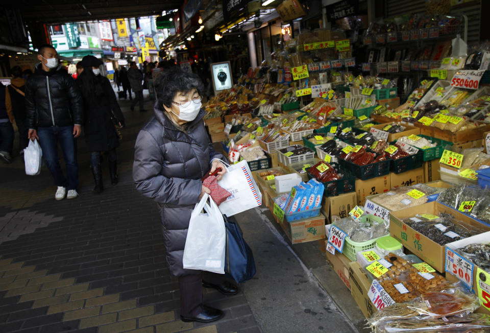 In this Wednesday, Feb. 12, 2014 photo, an elderly woman shops at a market in Tokyo. With government finances strained by Japan’s record-busting national debt, the country’s already Spartan social safety net is being cut further. Welfare rolls have risen to record levels as single parents and growing numbers of seniors lacking enough pension income seek help. (AP Photo/Junji Kurokawa)