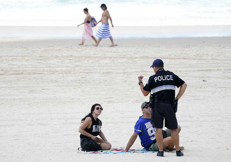 A policeman speaks with sunbathers on Surfers Paradise Beach on the Gold Coast.