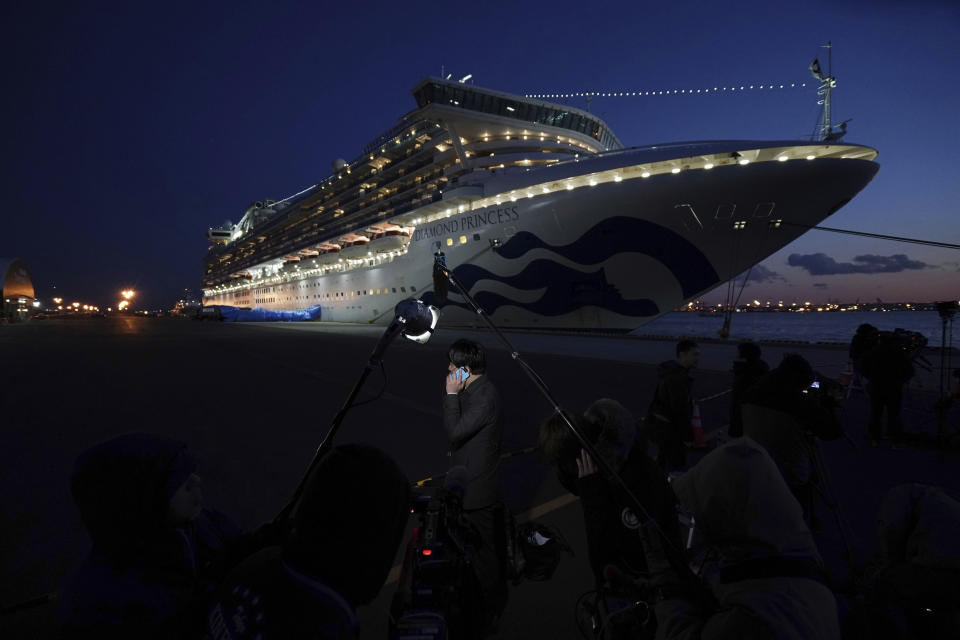 Journalists work near the quarantined Diamond Princess cruise ship sitting at the Yokohama Port Monday, Feb. 10, 2020, Yokohama, Japan. The operator of the ship said Monday that an additional 66 cases were found aboard. That is in addition to 70 reported earlier. (AP Photo/Eugene Hoshiko)