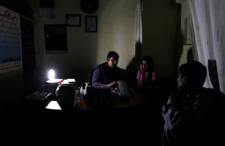 A homeopathic doctor speaks with the father of his patient at an infirmary during a power cut in Islamabad, Pakistan October 8, 2016. REUTERS/Caren Firouz