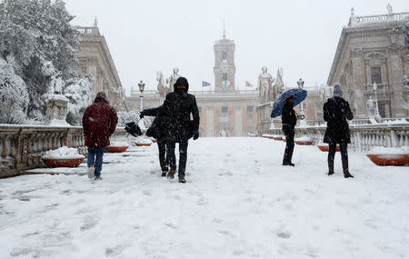 People walk at the Campidoglio palace during a heavy snowfall in Rome, Italy February 26, 2018. REUTERS/Remo Casilli