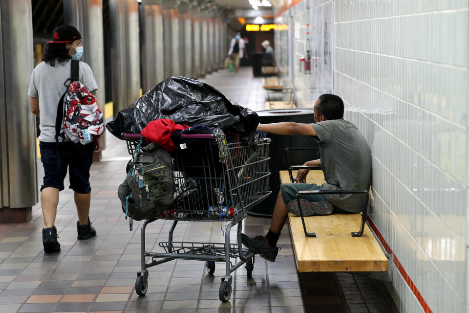 Ein wohnungsloser Mann mit seinen Besitztümern auf einer Bank in Boston. Die Zwischenlehnen sind so gestaltet, dass sich niemand auf der Bank hinlegen kann. (Bild: Jonathan Wiggs/The Boston Globe via Getty Images)