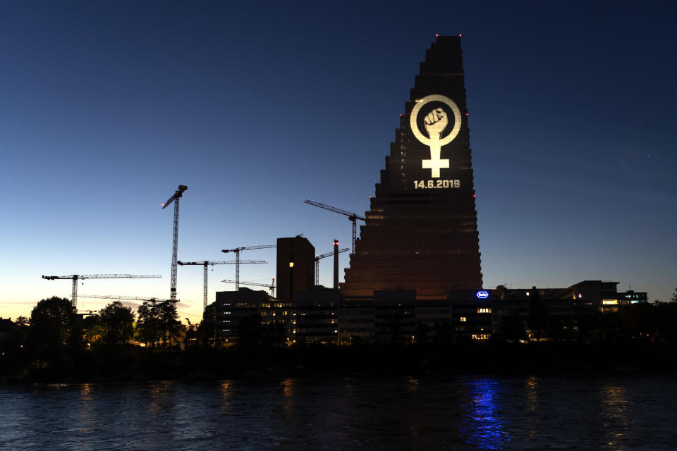 The women's strike logo is projected on the Roche Tower ahead of a nationwide women's strike on late Thursday, June 13, 2019, in Basel, Switzerland. There is list of several reasons motivating people to take part in the strike on 14 June. These range from unequal wages to pressures on part-time employees, the burden of household work and sexual violence. (Georgios Kefalas/Keystone via AP)