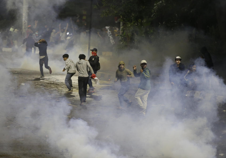 Student protesters run from tear gas fired by riot police during a clash in Jakarta, Indonesia, Monday, Sept. 30, 2019. Thousands of Indonesian students resumed protests on Monday against a new law they say has crippled the country's anti-corruption agency, with some clashing with police.(AP Photo/Achmad Ibrahim)