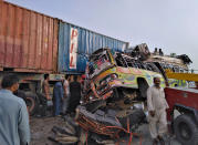 In this handout photo released by Punjab Province's Emergency Service Rescue 11222, shows residents and rescue workers at the site of a deadly bus accident near Dera Ghazi Khan, Pakistan, Monday, July 19, 2021. The speeding bus carrying mostly laborers traveling home for a major Muslim holiday rammed into a container truck on a busy highway in central Pakistan, killing and injuring dozens, police and rescue officials said. (Emergency Service Rescue 1122 via AP)