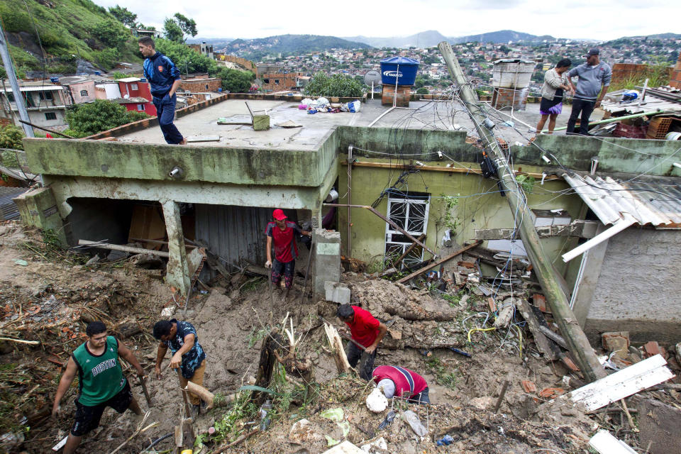 Locals work to clean up mud and debris around houses destroyed by a landslide after heavy rains in Vila Ideal neighborhood, Ibirite municipality, Minas Gerias state, Brazil, Saturday, Jan.25, 2020. Heavy rains caused flooding and landslides in southeast Brazil, killing at least 30 people, authorities said Saturday. (AP Photo/Alexandre Mota-Futura Press)