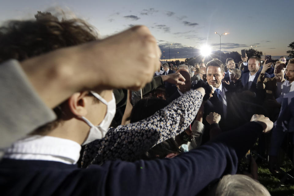 Supporters stretch their hands to touch fists with Presidential candidate Rafal Trzaskowski, right, at the end of the election day in Warsaw, Poland, Sunday, July 12, 2020. Voting ended in Poland's razor-blade-close presidential election runoff between the conservative incumbent Andrzej Duda and liberal, pro-European Union Warsaw Mayor Rafal Trzaskowski with exit polls showing the election is too close to call. (AP Photo/Petr David Josek)