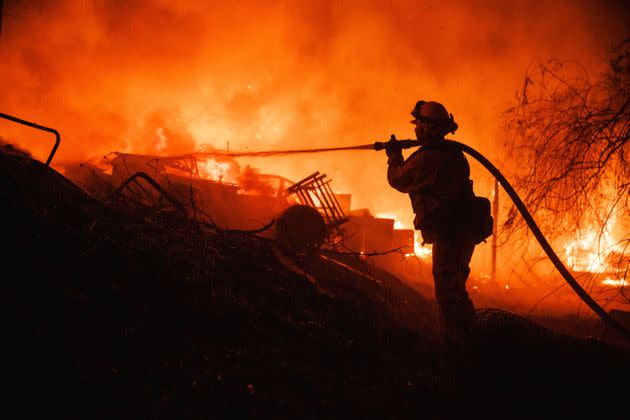 A firefighter takes a hose to a burning property while battling the Fairview Fire on Sept. 5, 2022, near Hemet, Calif. (Photo: Ethan Swope via AP)