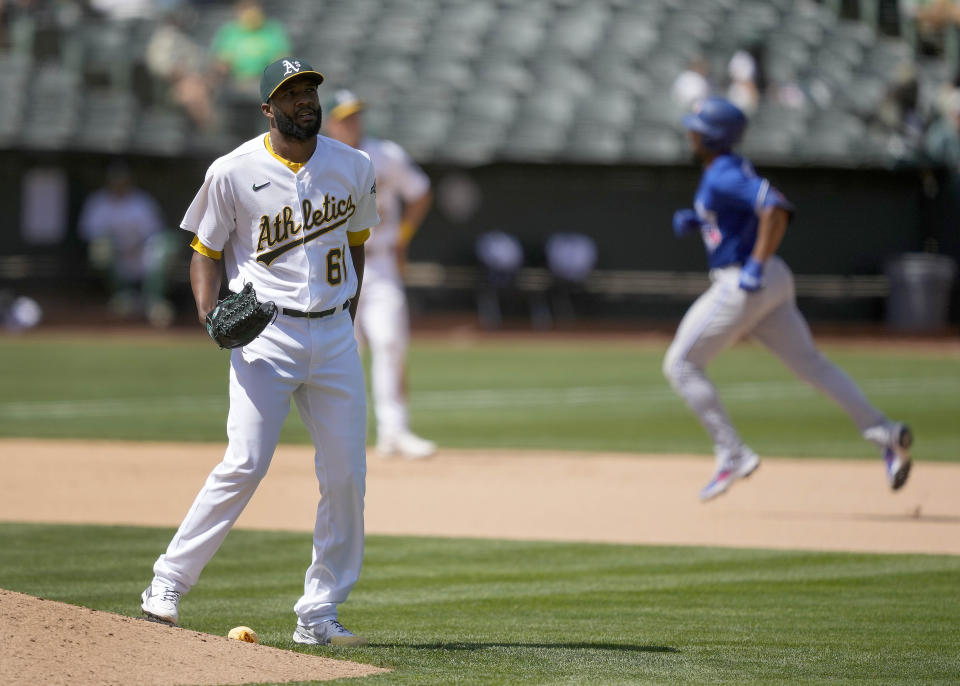 Oakland Athletics relief pitcher Reymin Guduan (61) stands on the edge of the mound as Toronto Blue Jays' Marcus Semien, right, runs the bases after hitting a solo home run during the seventh inning of a baseball game in Oakland, Calif., Wednesday, May 6, 2021. (AP Photo/Tony Avelar)